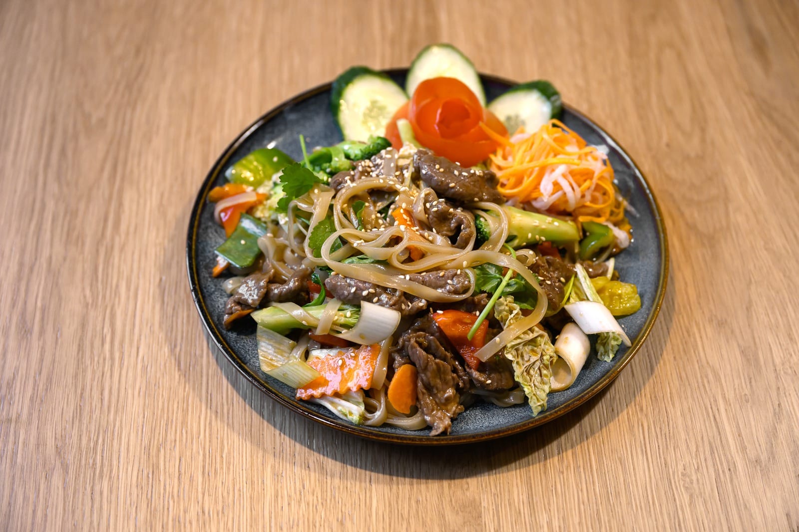 Wok-fried noodles with pork and peppers on a ceramic plate